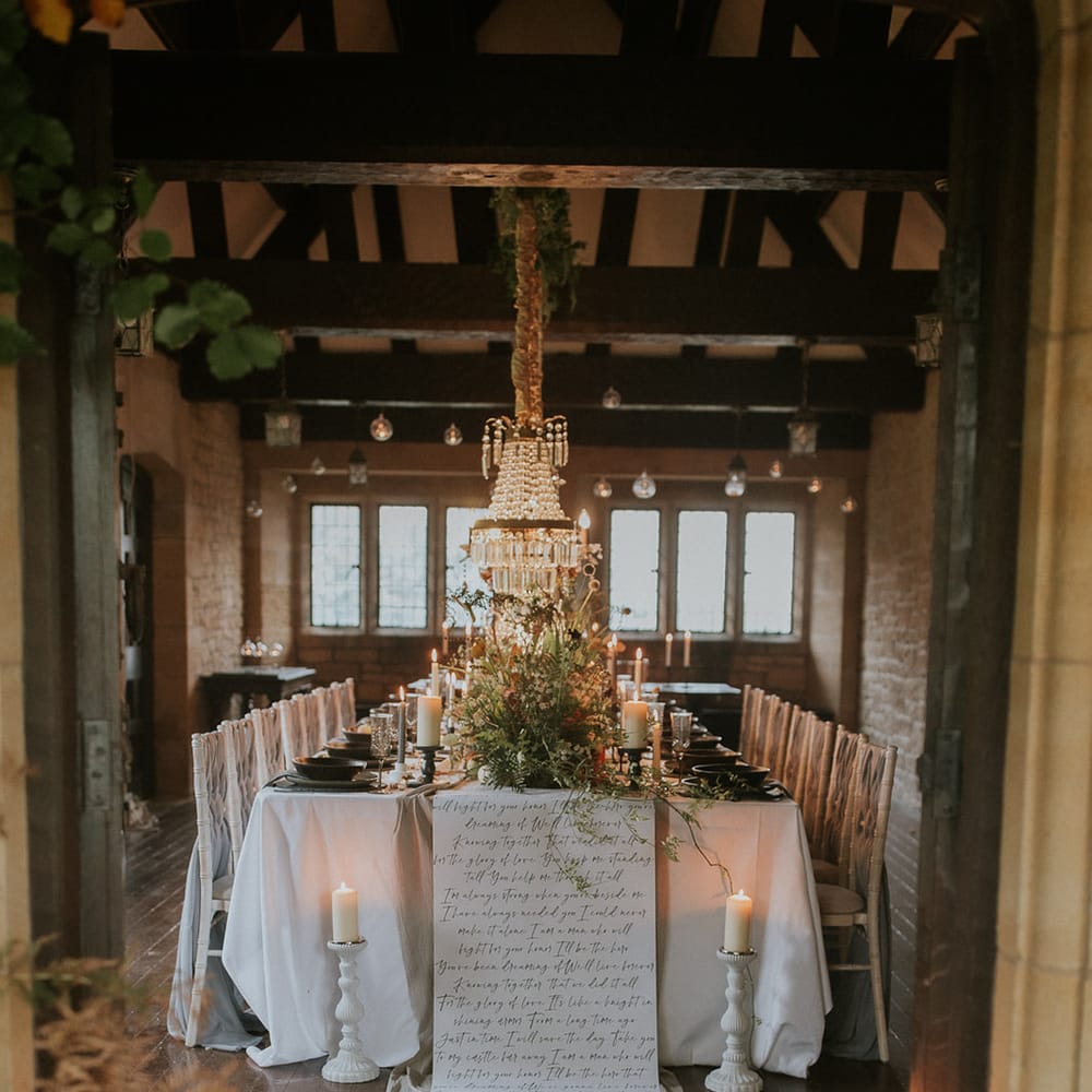 Intimate wedding table at Hooton Pagnell Hall with chandelier installation and script table cloth 
