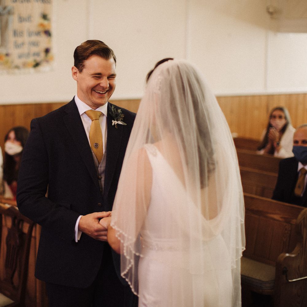 Bride & groom hold hands during wedding ceremony