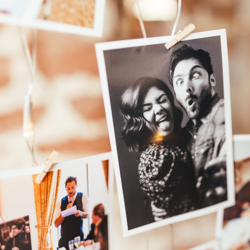 Black and white photo of bride and groom on wedding photo wall with fairy lights for rustic barn wedding reception 