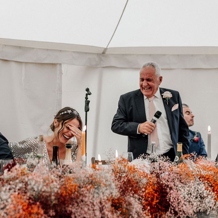 Bride and groom laughing during the wedding speeches with coloured gypsophila cloud top table wedding flowers 