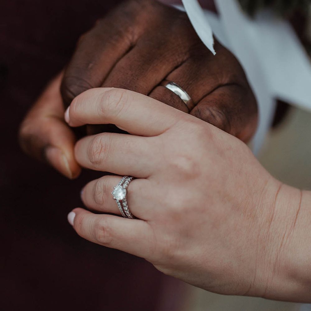 Bride & groom hold hands on their wedding day wearing wedding bands