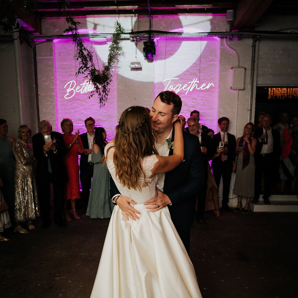 Couple have their first dance at London wedding venue, 100 Barrington with neon pink 'Better Together' sign
