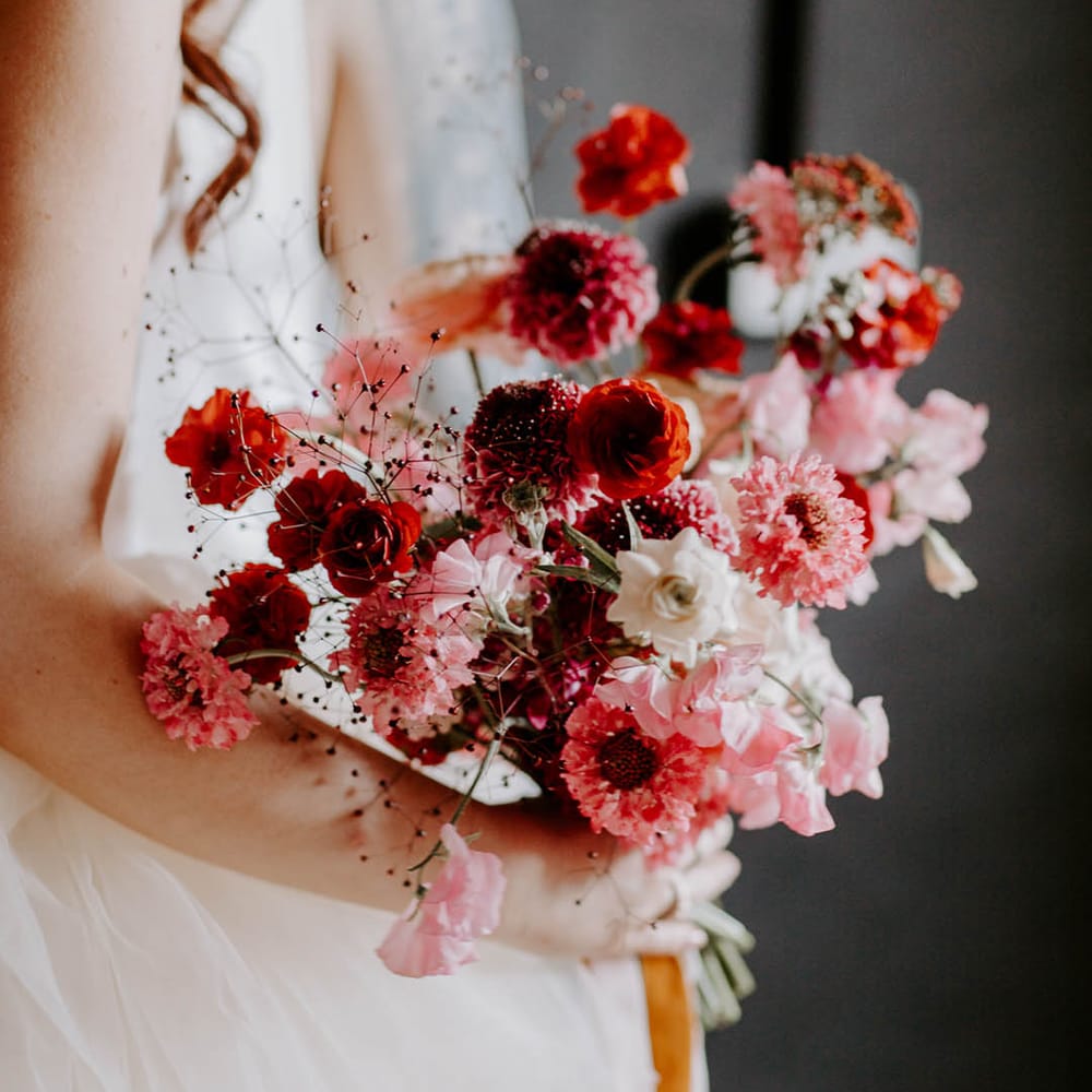 Romantic red and pink wedding bouquet with sweet peas and butterfly ranculus 