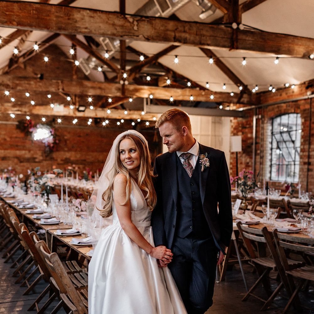 Bride in a princess wedding dress and pearl headband holding hands with her husband in their reception room at The Loft Studios 