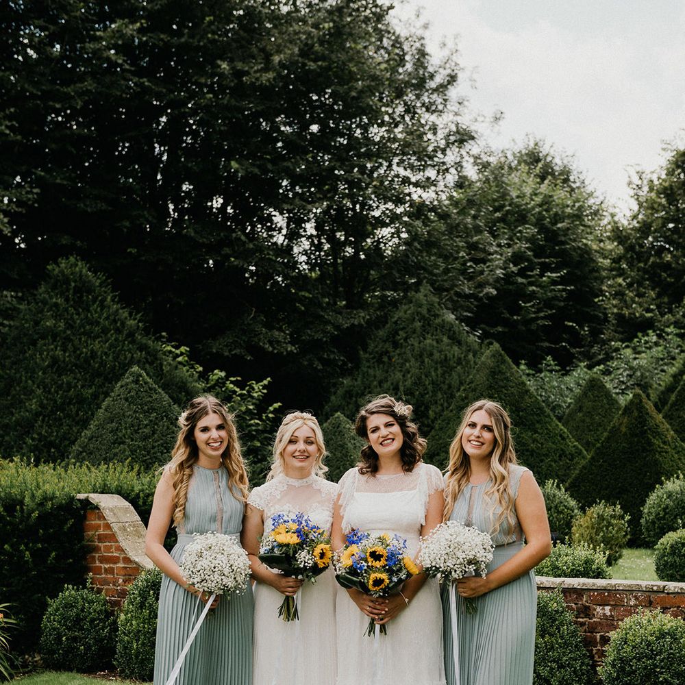 Brides pose with their bridesmaids in green pleated dresses on their wedding day
