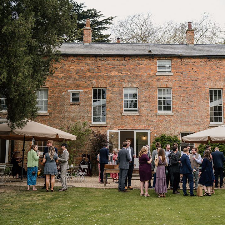 Wedding guests mingle and drink outside of the Aswarby Rectory wedding venue 