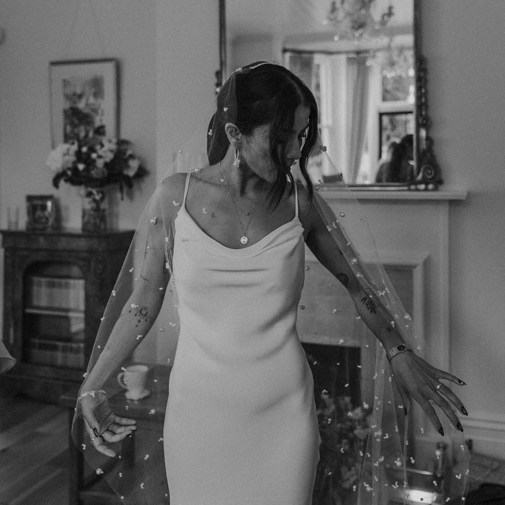 Bride in a satin slip wedding dress with bespoke pearl wedding veil on the wedding morning 