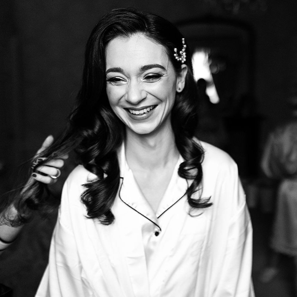 Bride wears her dark hair in curls pinned to one side with pearl hair accessory 