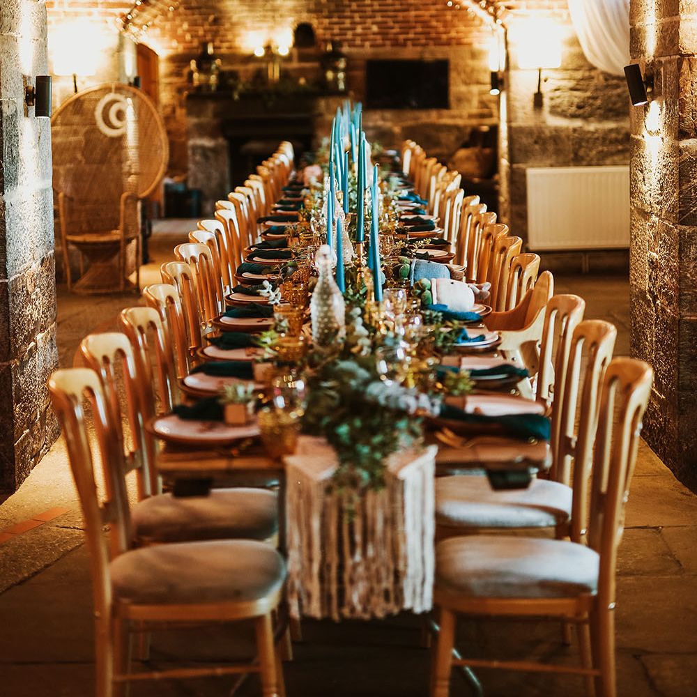 Boho wedding reception complete with blue candles and plant wedding favours with macrame table runner
