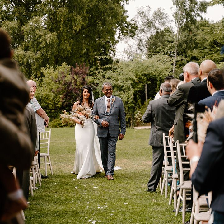 Groom holding the son with the father of the bride walking the bride down the aisle 