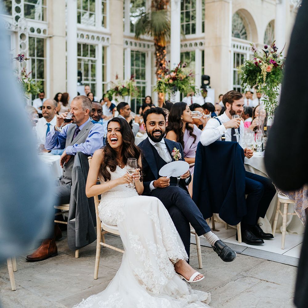 Bride & groom laugh during wedding speeches in the Great Conservatory at Syon Park