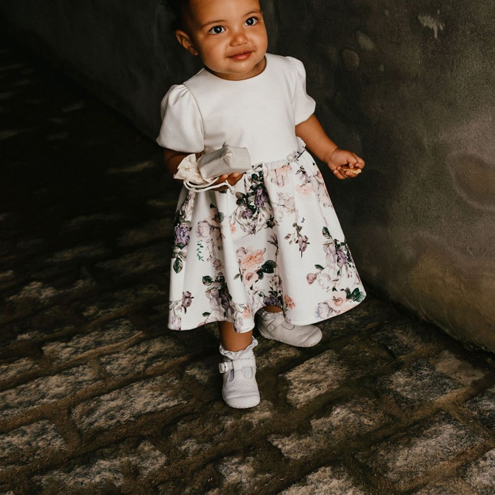 Flower girl in a flowery dress and bow in her hair 