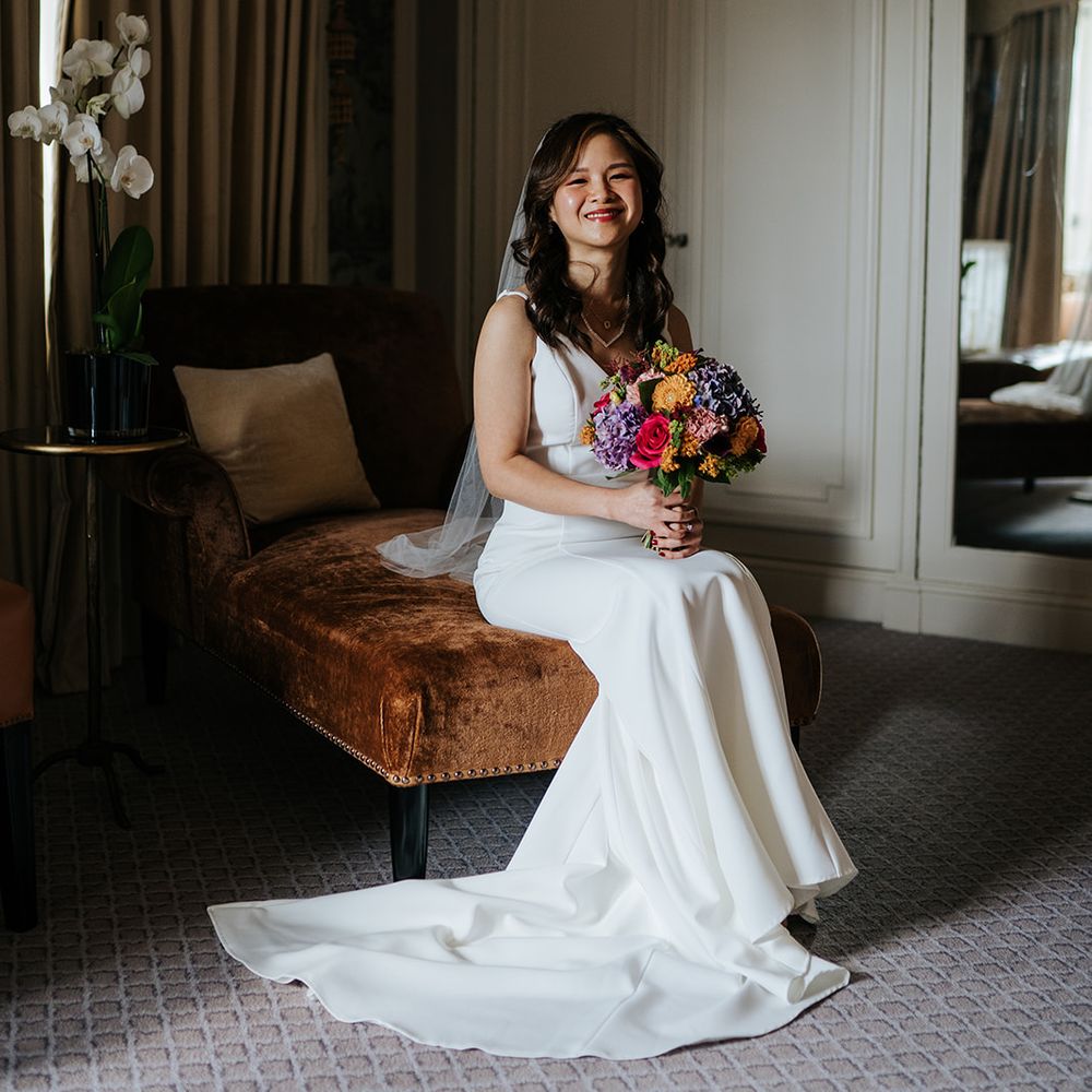 East Asian bride holds brightly coloured bouquet at The Dorchester before wedding day