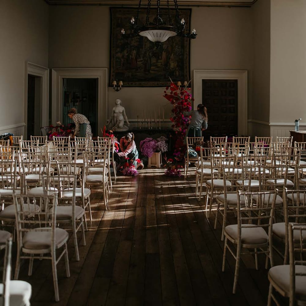 Reception room of Elmore Court with large hanging modern chandelier and large floral decor with dahlias, orchids, roses, amaryllis, anthuriums and dried flowers 