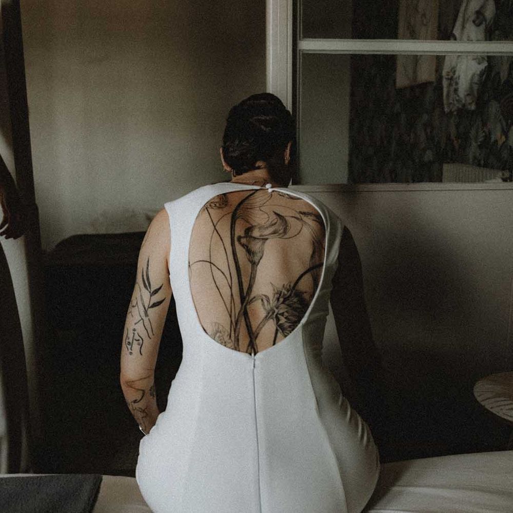 Lisa wears wears open back fitted pre loved wedding dress and showcases back tattoo