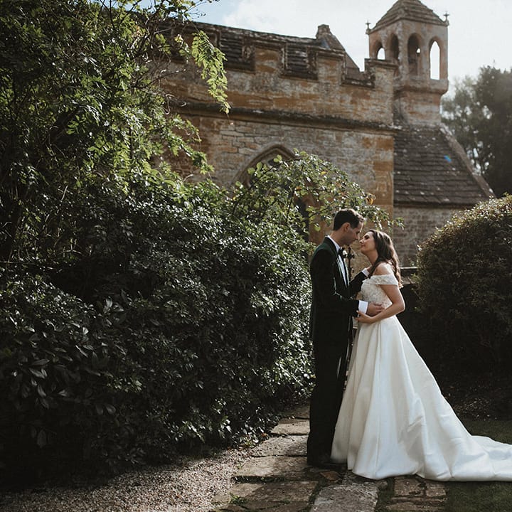 Traditional and classic country house wedding venue with the bride and groom standing together leaning in for a kiss 