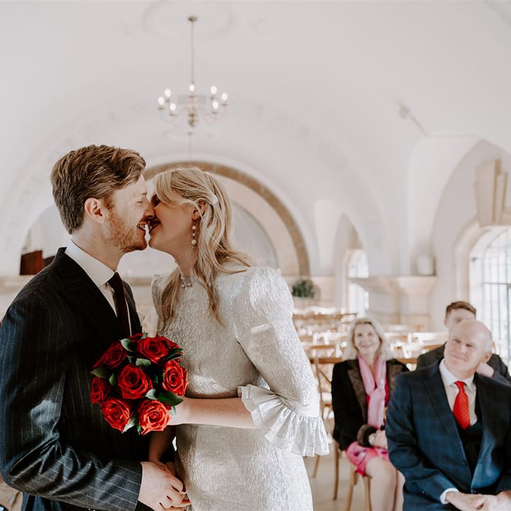 The bride and groom lean in to share three first kiss together as a married couple at their Halloween wedding 