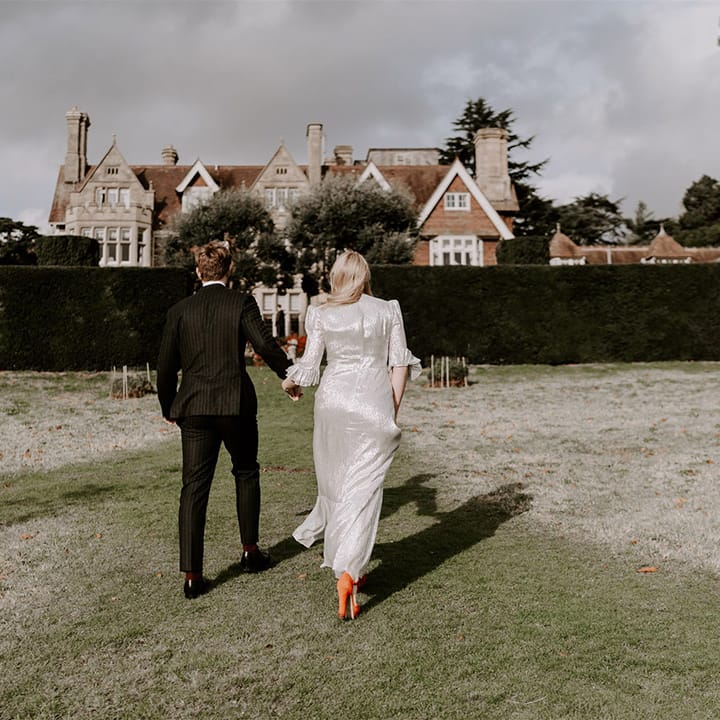 Bride in metallic wedding dress with bright orange wedding shoes with the groom in pinstriped suit for gothic wedding
