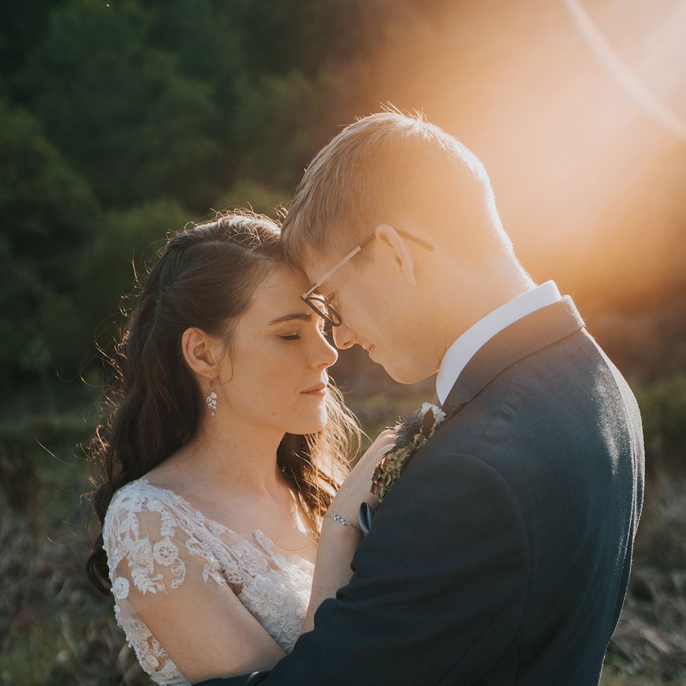 The bride and groom rest their foreheads against each other for golden hour portraits on their wedding day 