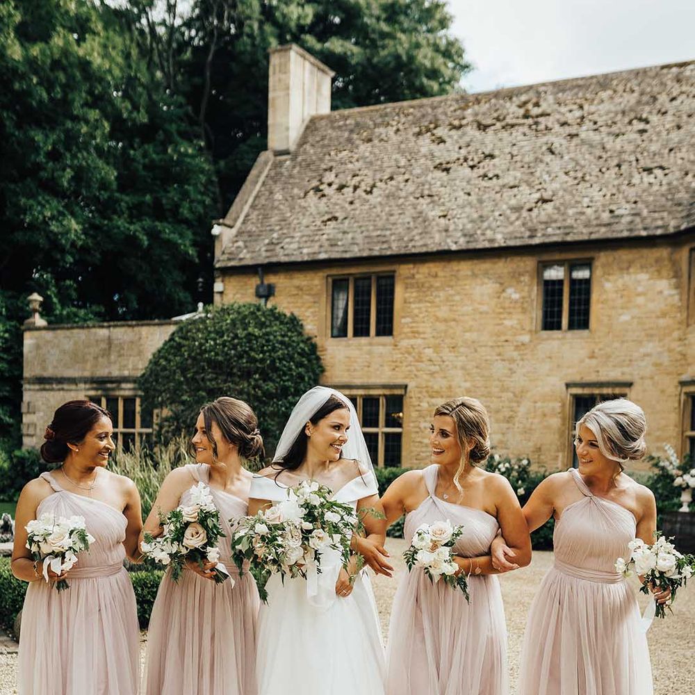 Bride in off the shoulder wedding dress walking with bridal party wearing light pink bridesmaid dresses