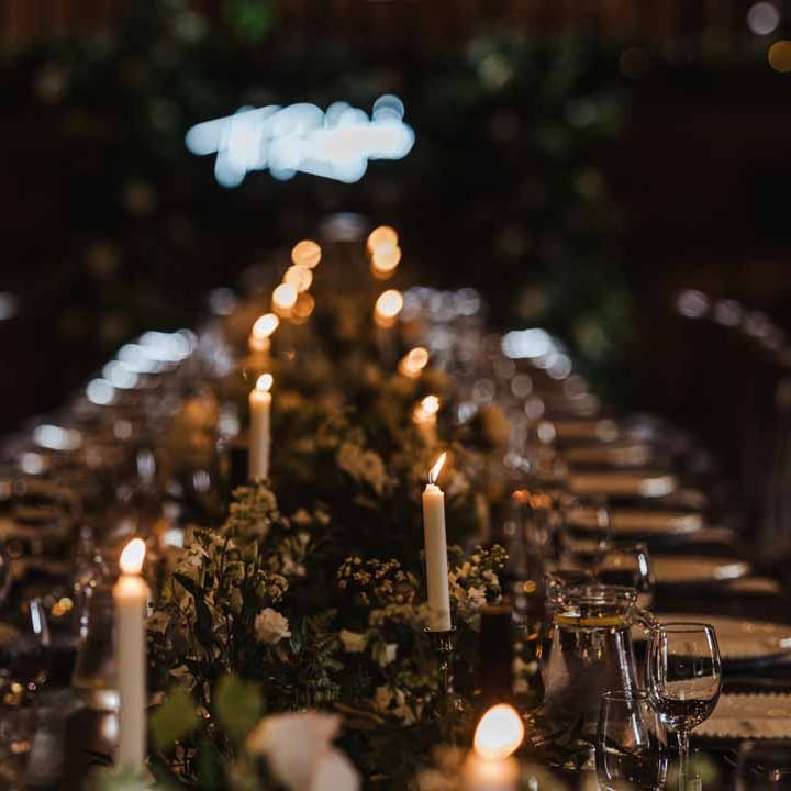 Botanical rustic wedding tablescape with white pillar candles, foliage table runners, white garden rose, hydrangea and cows parsley centrepieces and white wedding napkins 