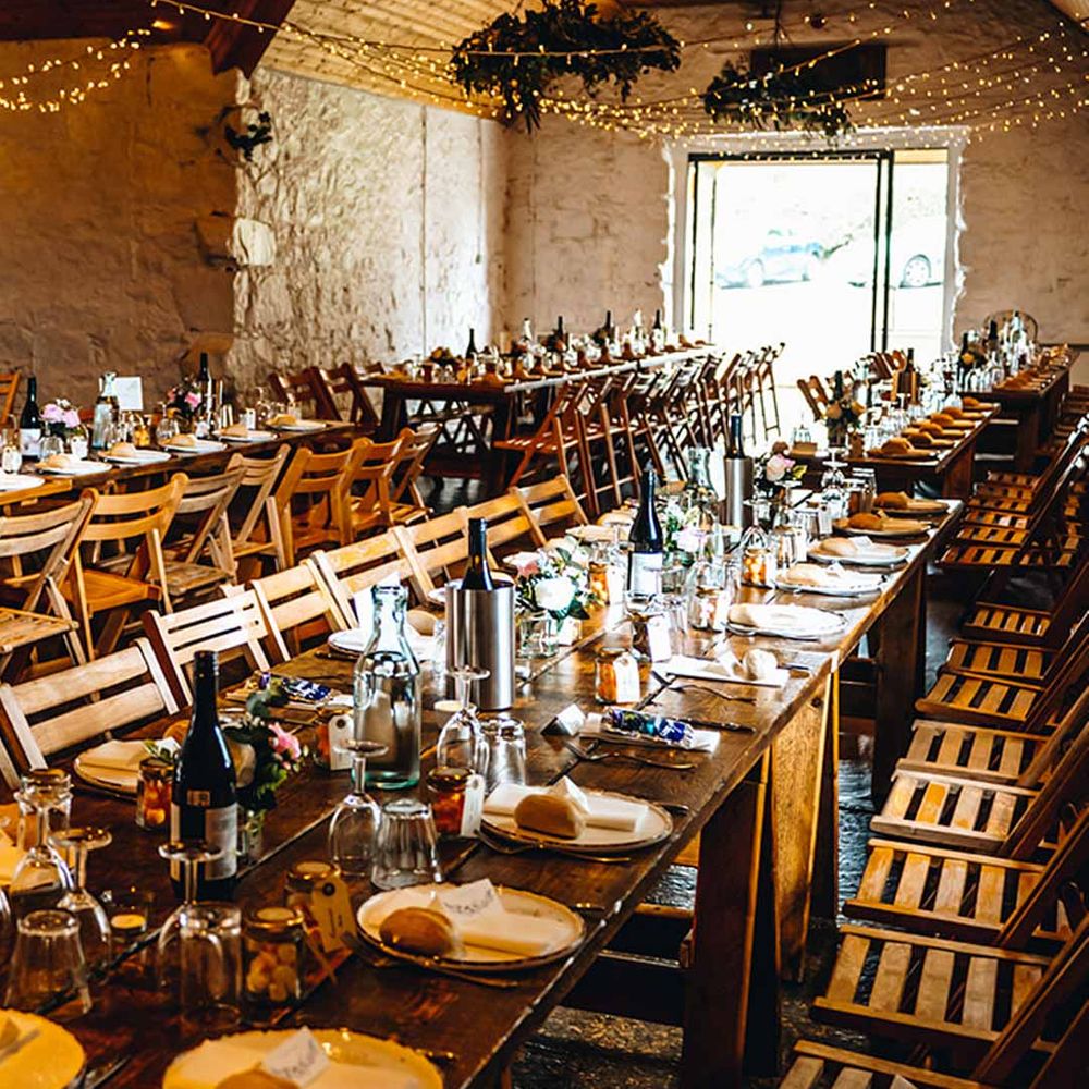 Classic warm rustic wedding tablescape at Dalduff Luxury Barn wedding venues Scotland with fairy lights and suspended foliage decorations 