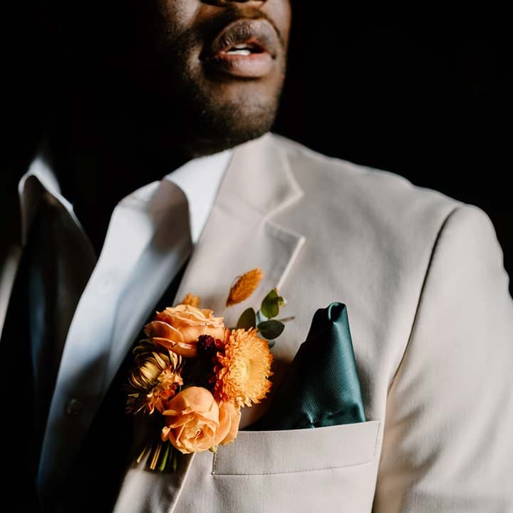 Groom in light grey grooms morning suit with white shirt, forest green pocket square and orange boutonniere 