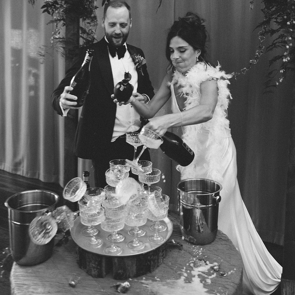 Champagne tower fail for the bride and groom who topple the tower over as they pour the champagne 