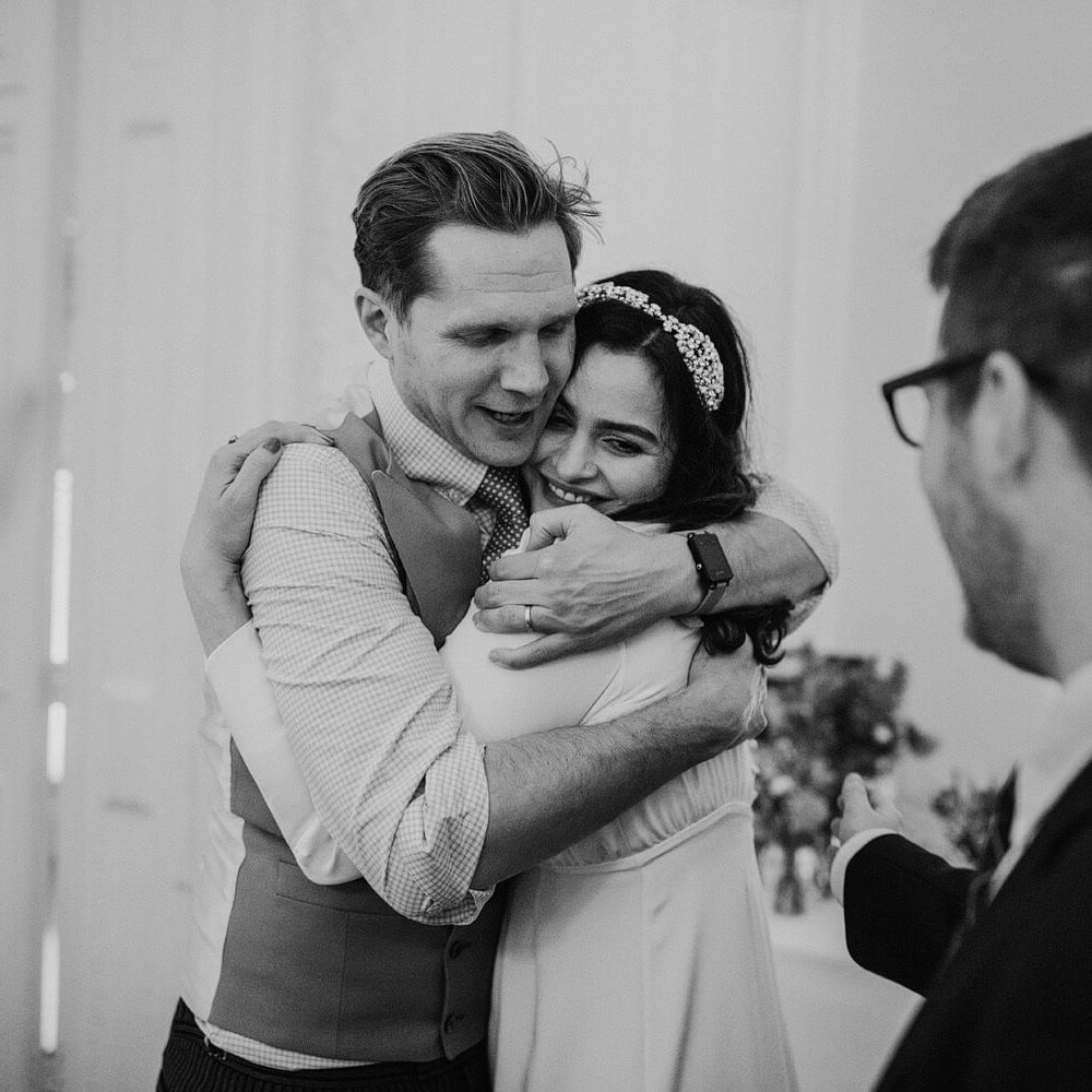 Wedding guest hugging newly wed bride - Black and white wedding day photography