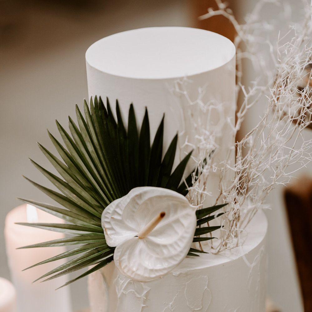 Two tier white wedding cake with palm leaf and white anthurium flower decoration