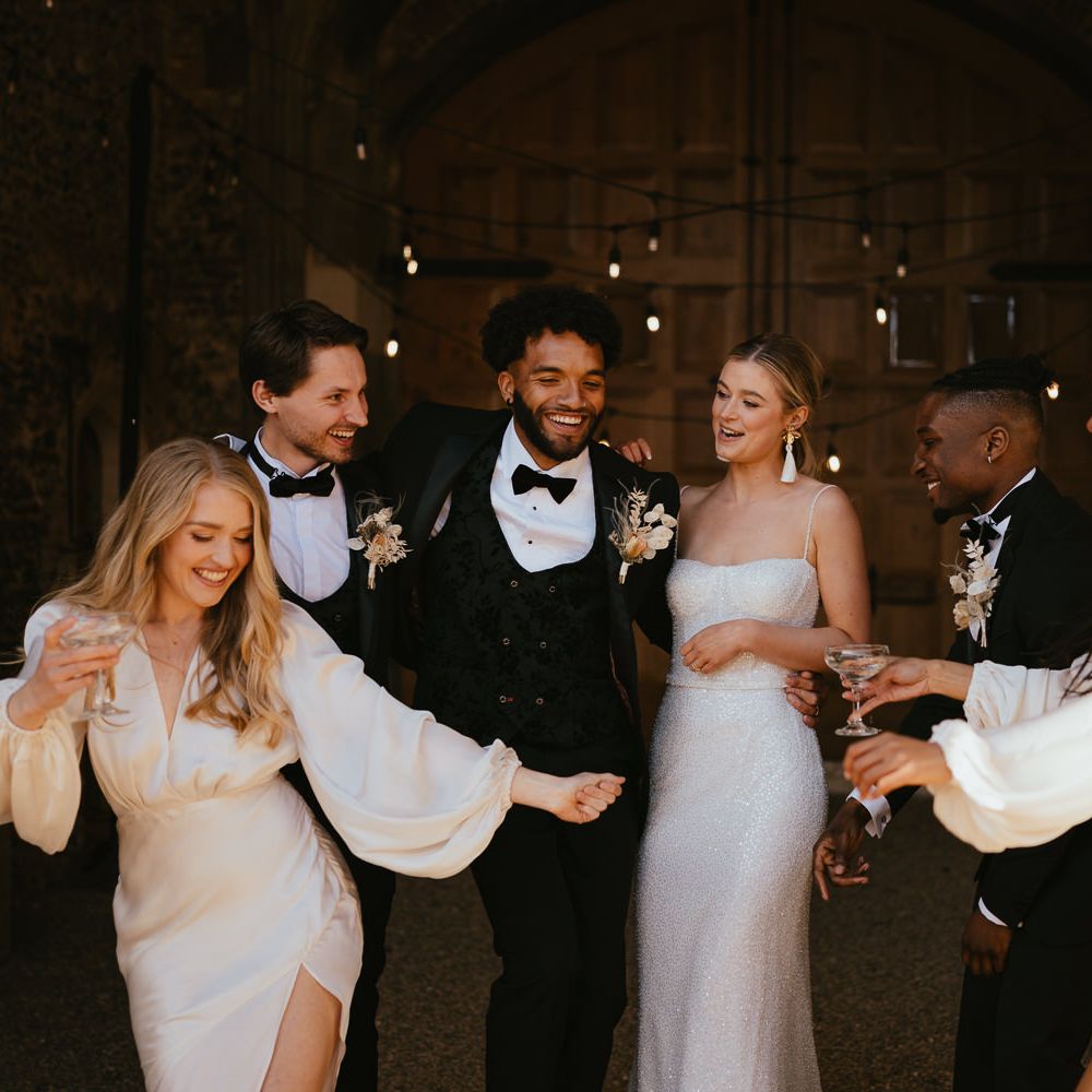 Wedding party portrait with bridesmaids in champagne satin dresses, and the groomsmen in black tie suits 