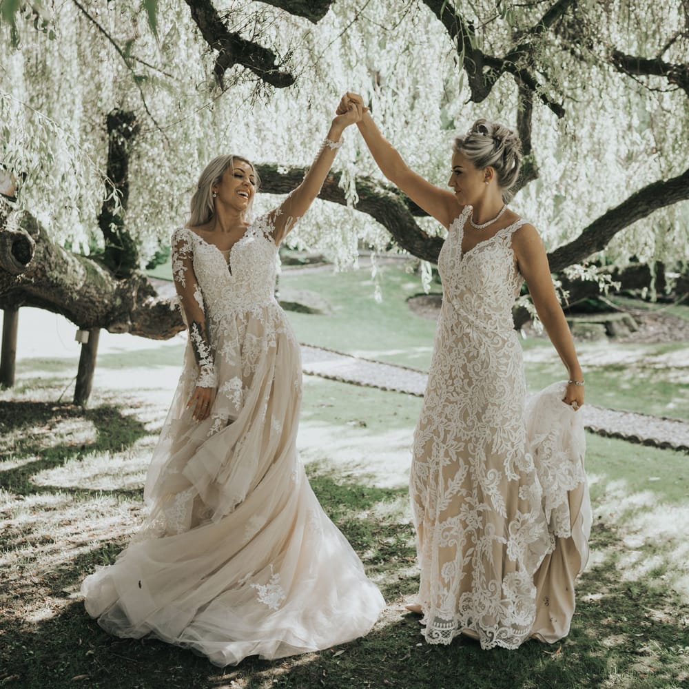 Two brides dance under the trees at Crab & Lobster fairytale wedding.