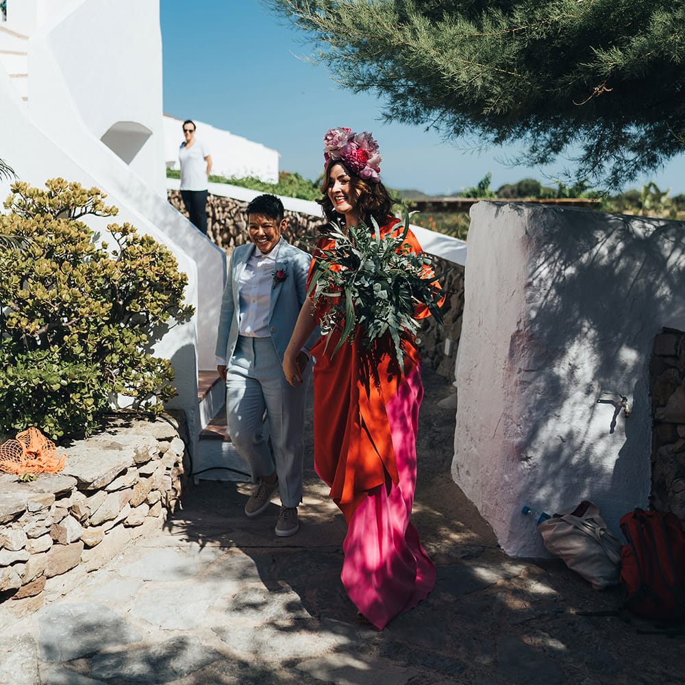 Brides walk down steps on their wedding day as the sun shines
