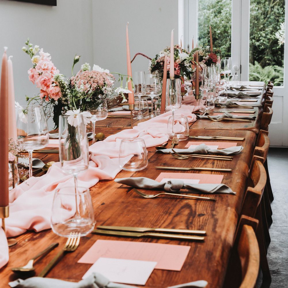 Pastel pink and peach colour scheme for tablescape complete with pink cloth table runner, pink candles and gold cutlery