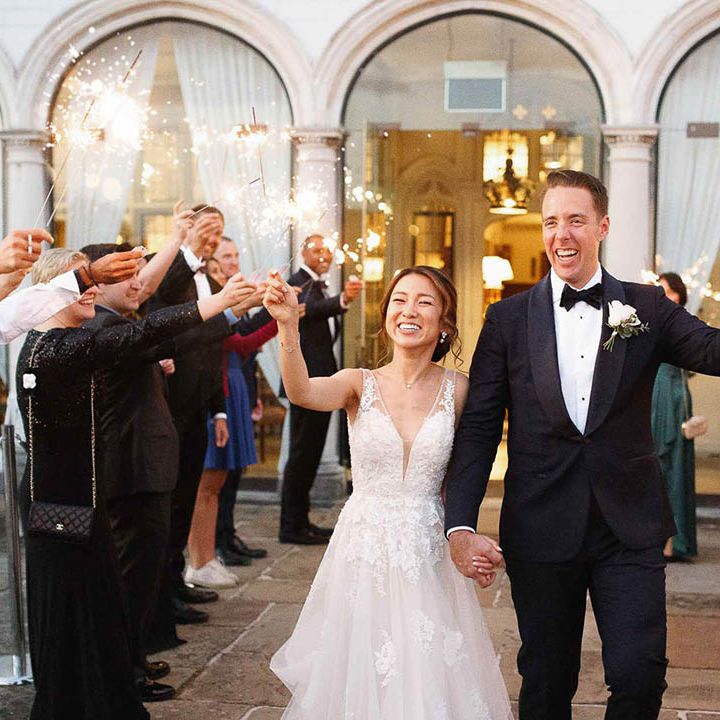Bride & groom and wedding guests hold sparklers outdoors