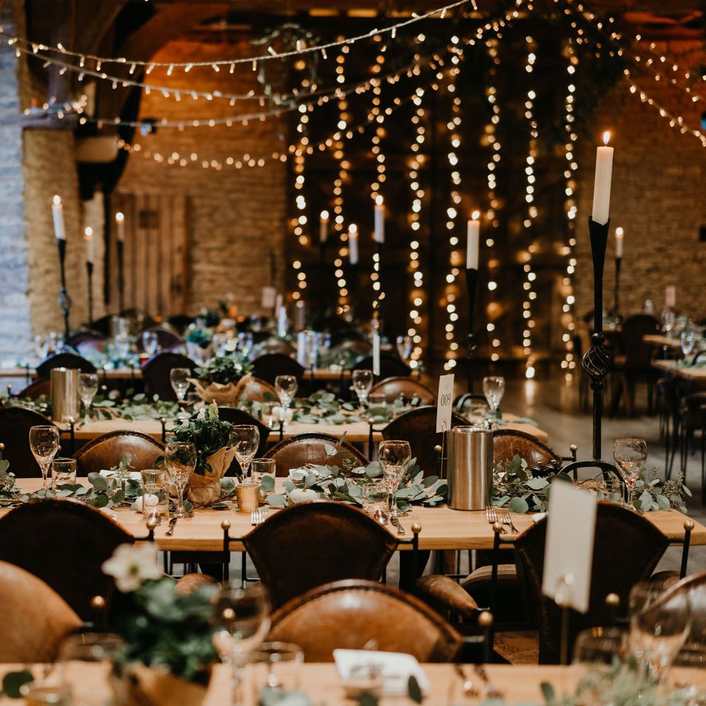 Rustic barn wedding reception with candles, fairy light, wooden tables and table garlands
