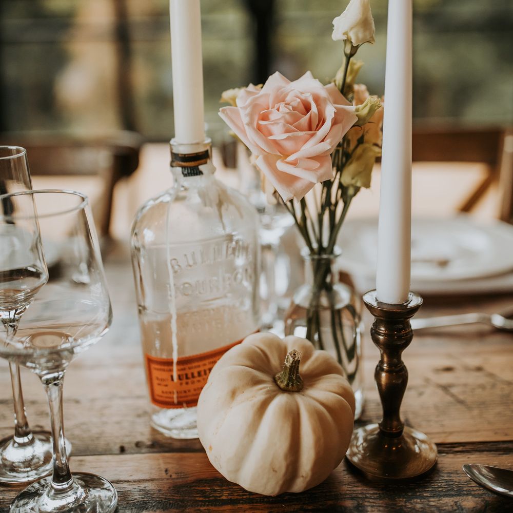Pink rose in glass bud vase with candles and small white pumpkin for rustic wedding table decor