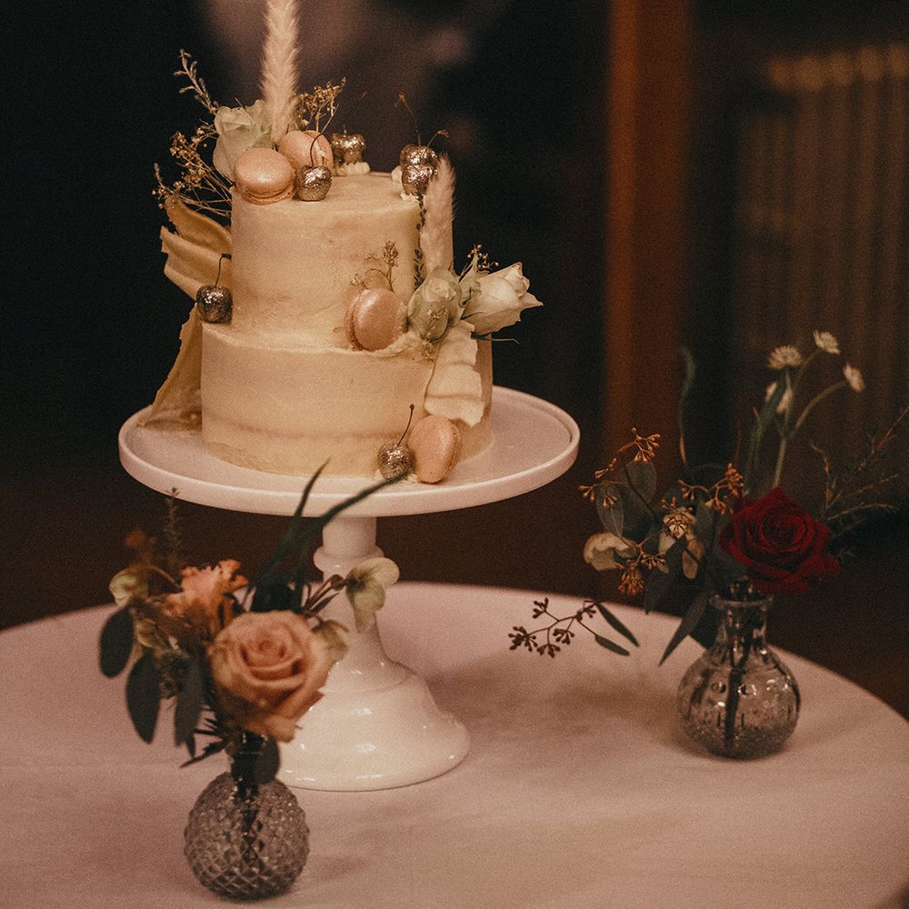 2 tier wedding cake complete with light frosting, macaroons and silver dipped cherries 