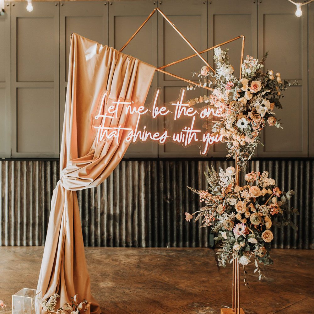Gold Fram wedding arch with pink draping, mixed flower clouds and pink neon wedding sign