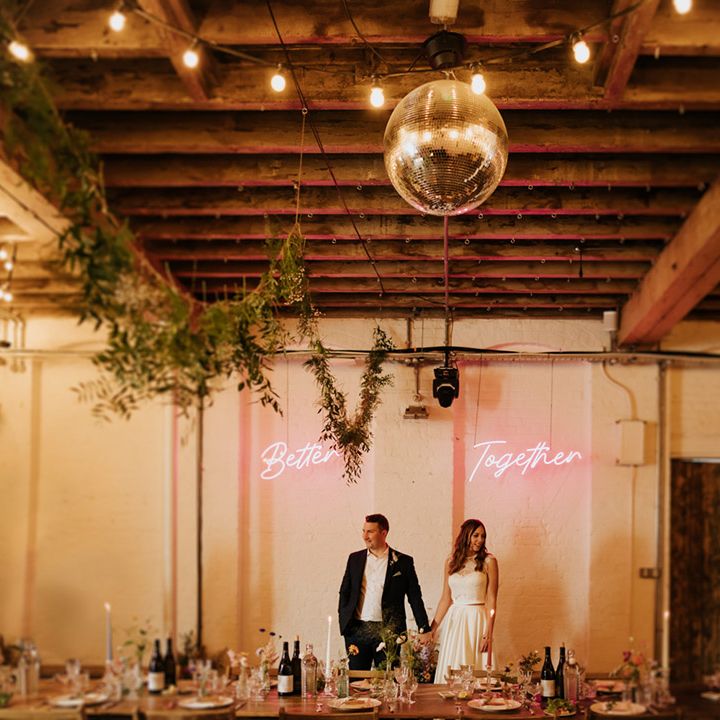 Bride and groom at 100 Barrington wedding venue with neon pink 'Better Together' sign and disco ball 