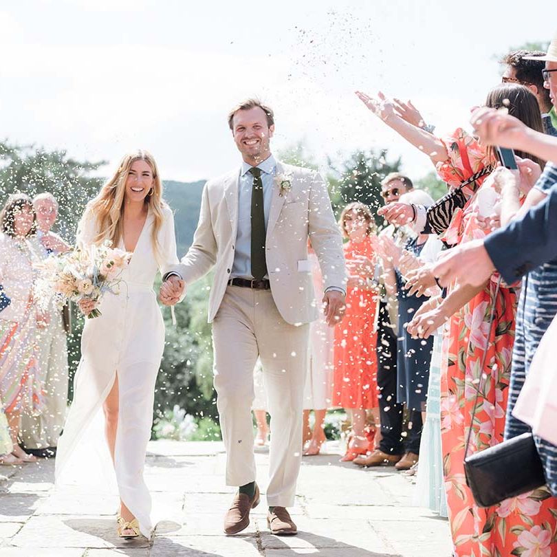 Bride in bespoke Bon Bride dress and groom have their confetti exit at their garden wedding in summer in Bath