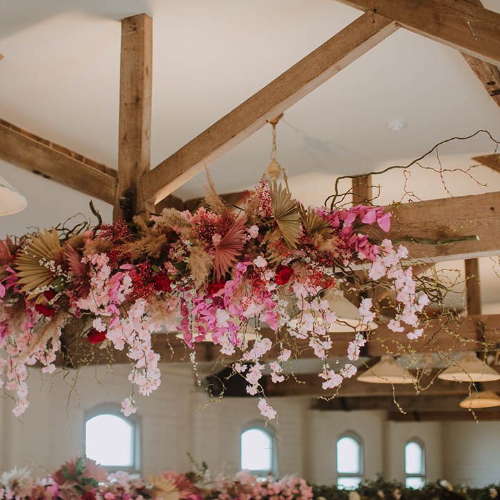 Prestwold Hall Barn exposed beams decorated in cherry blossom, dried grasses and pink flowers 