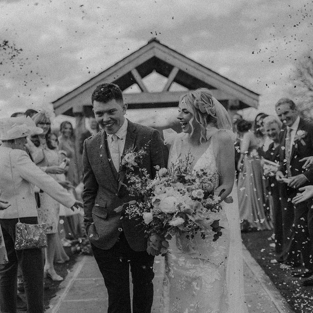 Bride with braided hairstyle smiles as she has confetti exit with the groom 
