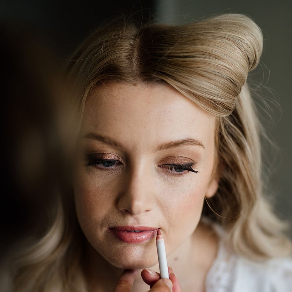 Bride gets her makeup done with a pink lip and gold eyeshadow with a soft wing 