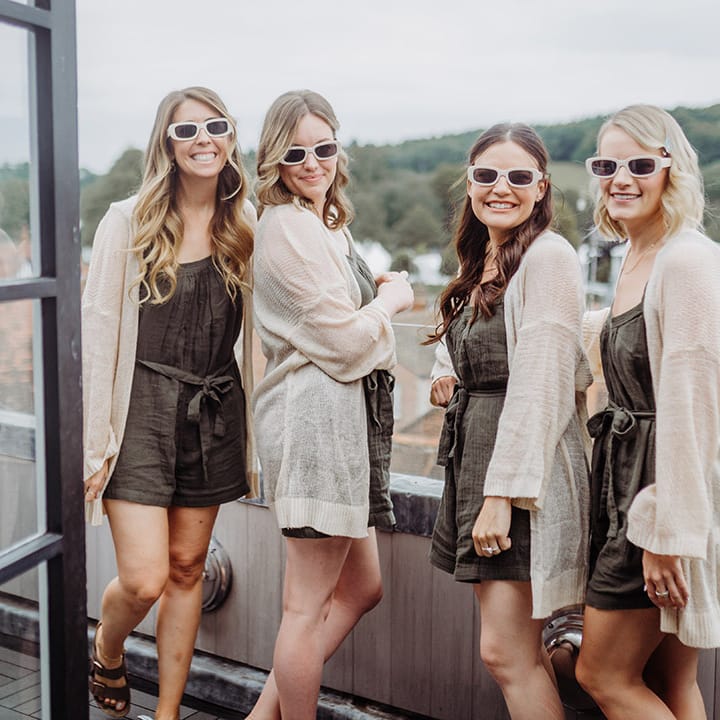 Bridesmaids in sunglasses and matching khaki playsuits and cardigans 
