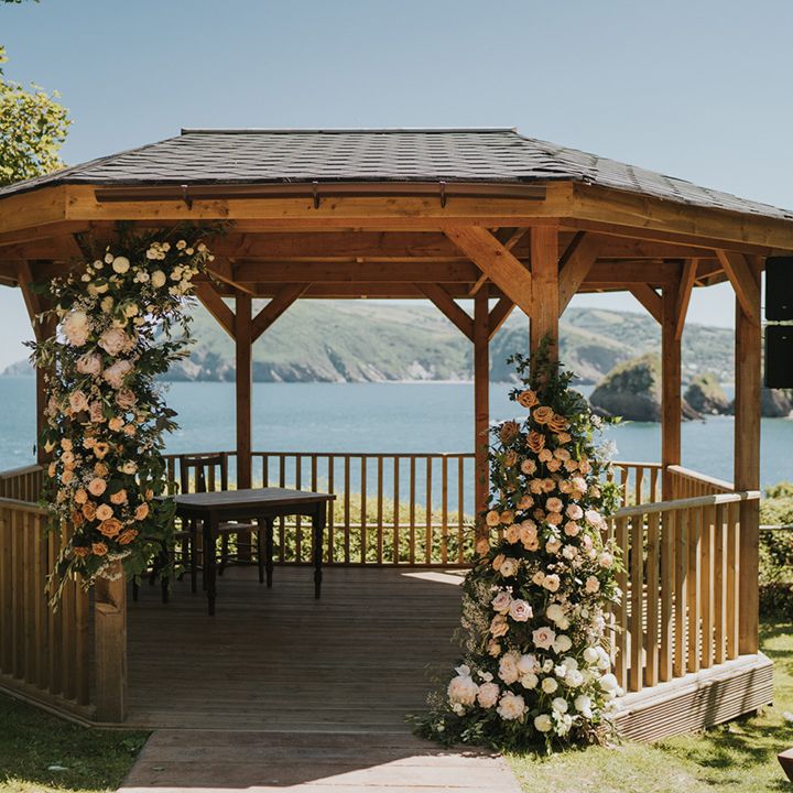 Outdoor pergola complete with flower installation with white roses and green foliage