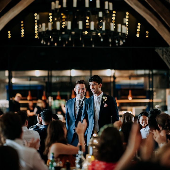 Grooms wear matching suits complete with white floral buttonholes during barn reception 