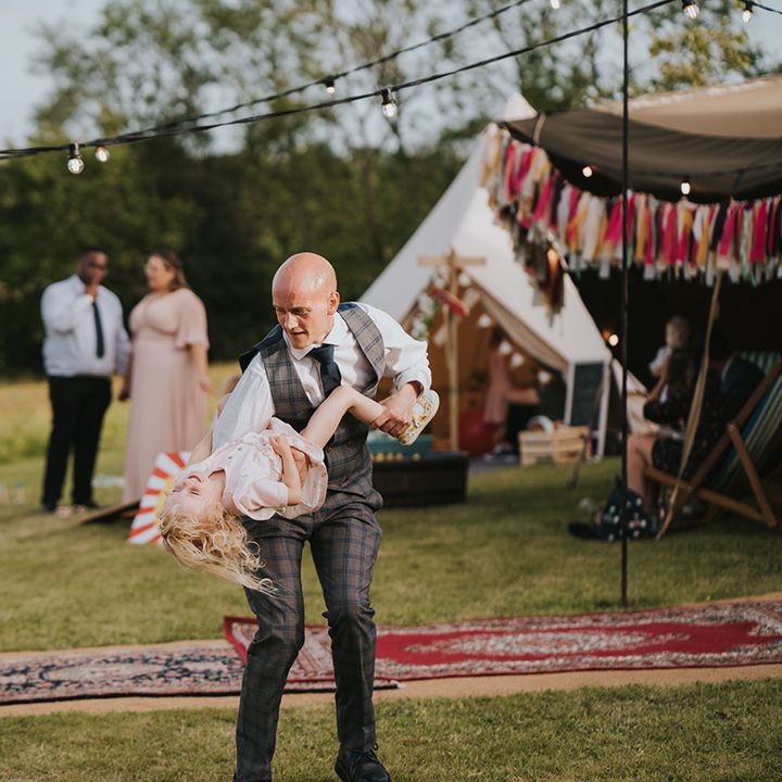 Wedding guest plays with child outdoors in front of Moroccan styled carpets 