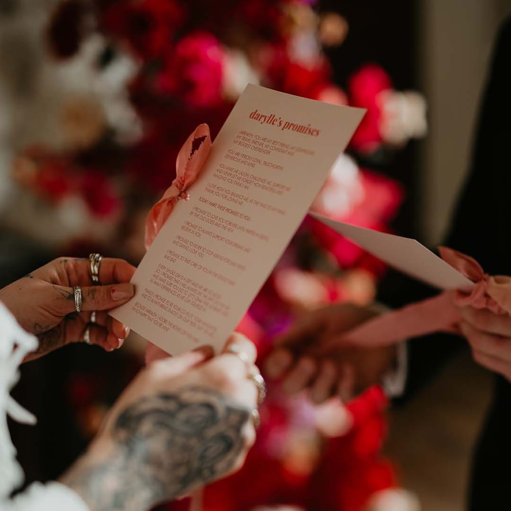Retro wedding vows stationery with hot pink lettering and a baby pink ribbon on off white paper 