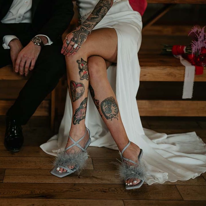 Groom in black suit trousers and black patent groom shoes and bride in soft grey fluffy feather open toe strappy high heels 